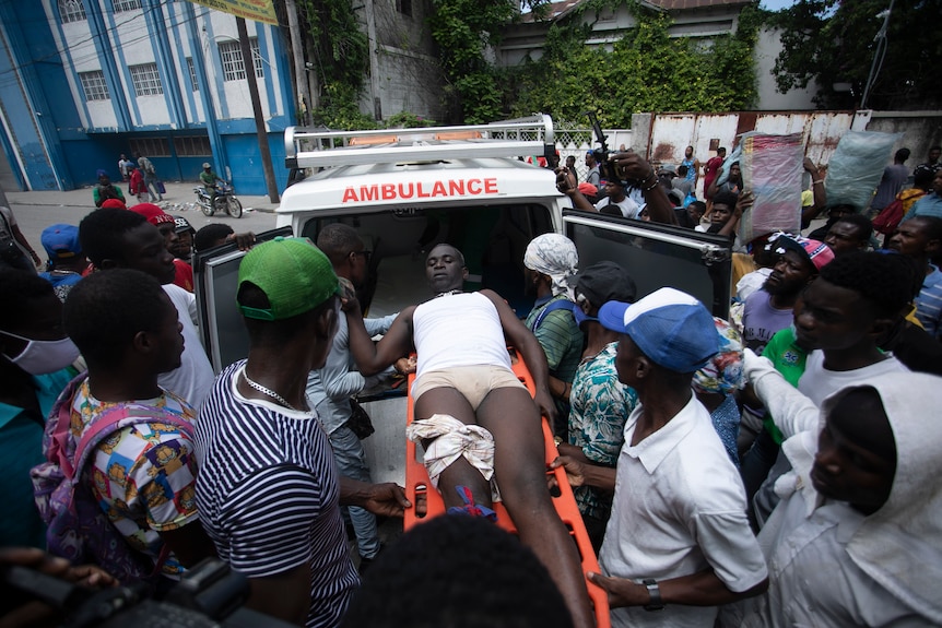 Un manifestante que recibió un disparo de la policía en la pierna es trasladado a una ambulancia por otras personas