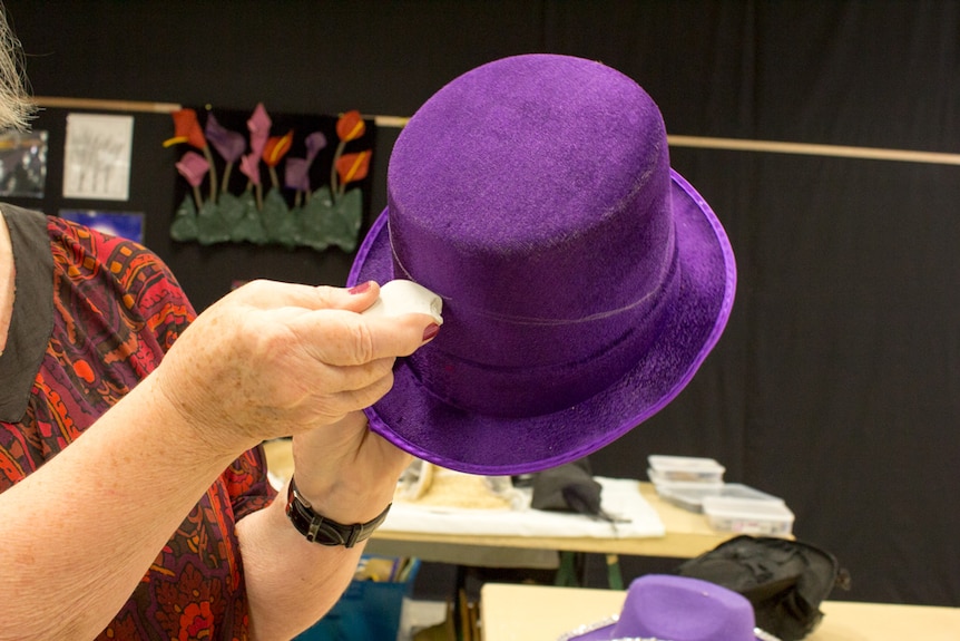 Marking a chalk line on a felt hat before removing the brim.