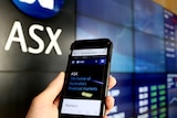 A mobile phone is held in a person's hand at the ASX in Sydney