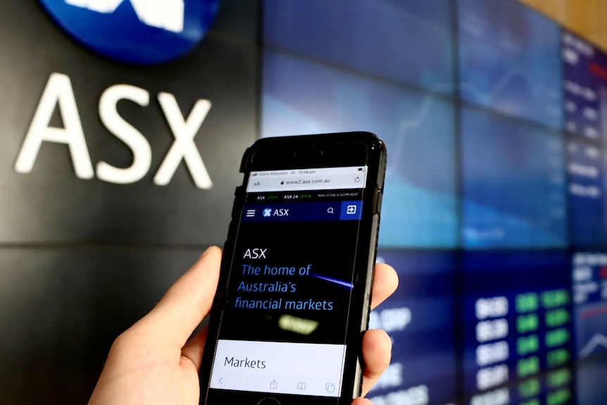 A mobile phone is held in a person's hand at the ASX in Sydney