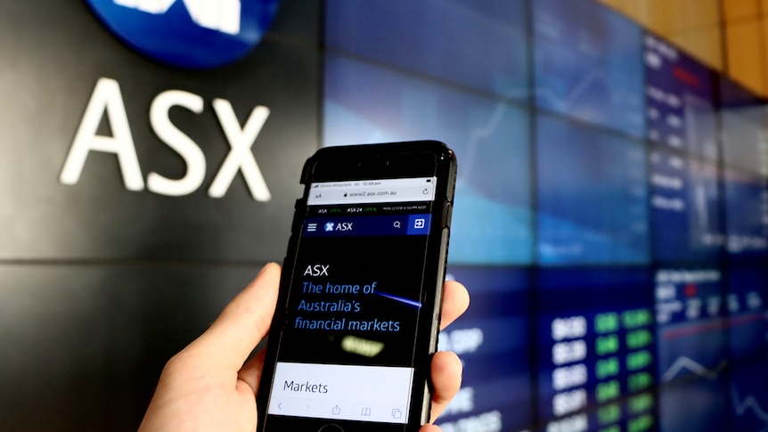 A mobile phone is held in a person's hand at the ASX in Sydney