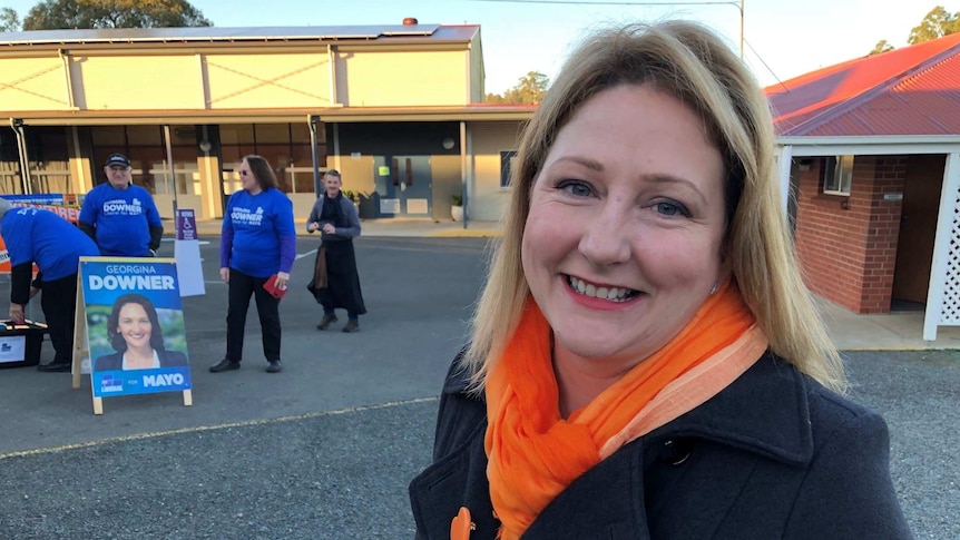A woman smiles at the camera with liberal election volunteers in the background