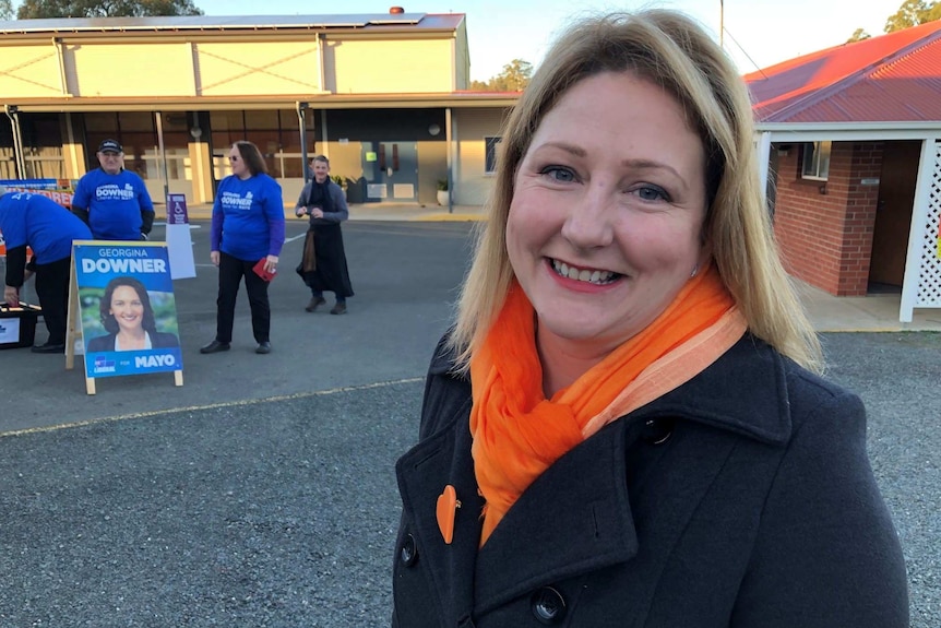 A woman smiles at the camera with liberal election volunteers in the background