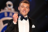 Patrick Cripps smiles and holds the Brownlow Medal while wearing it around his neck