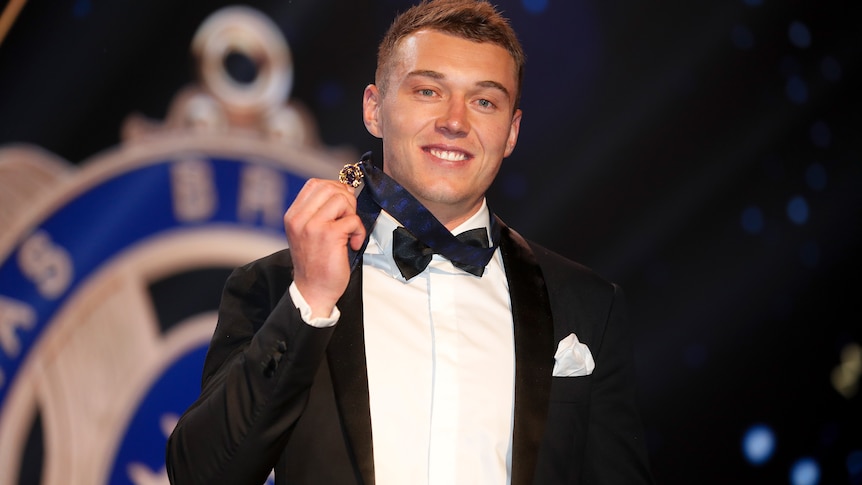 Patrick Cripps smiles and holds the Brownlow Medal while wearing it around his neck