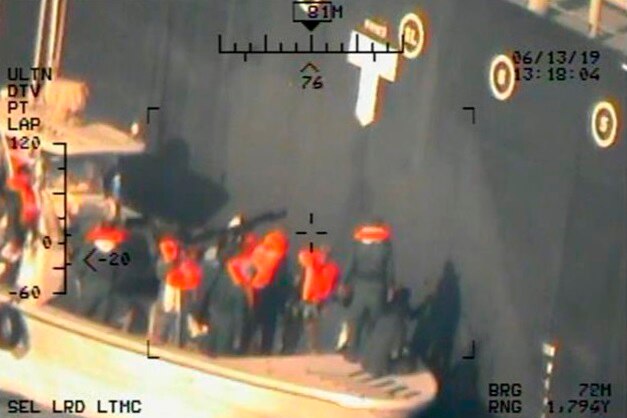 Image released by US shows what the Navy says are Iranian soldiers removing a mine from a ship.
