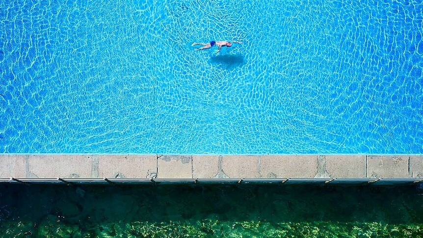 A drone photo of swimmers in an ocean pool.