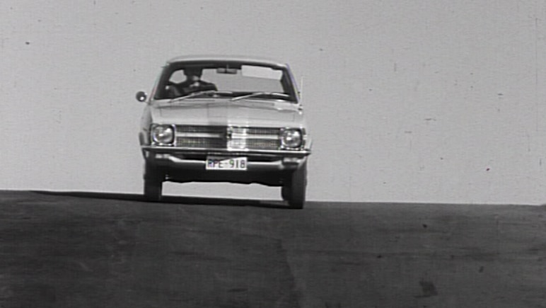 A Holden Torana comes over the hill in a black and white still from a film.