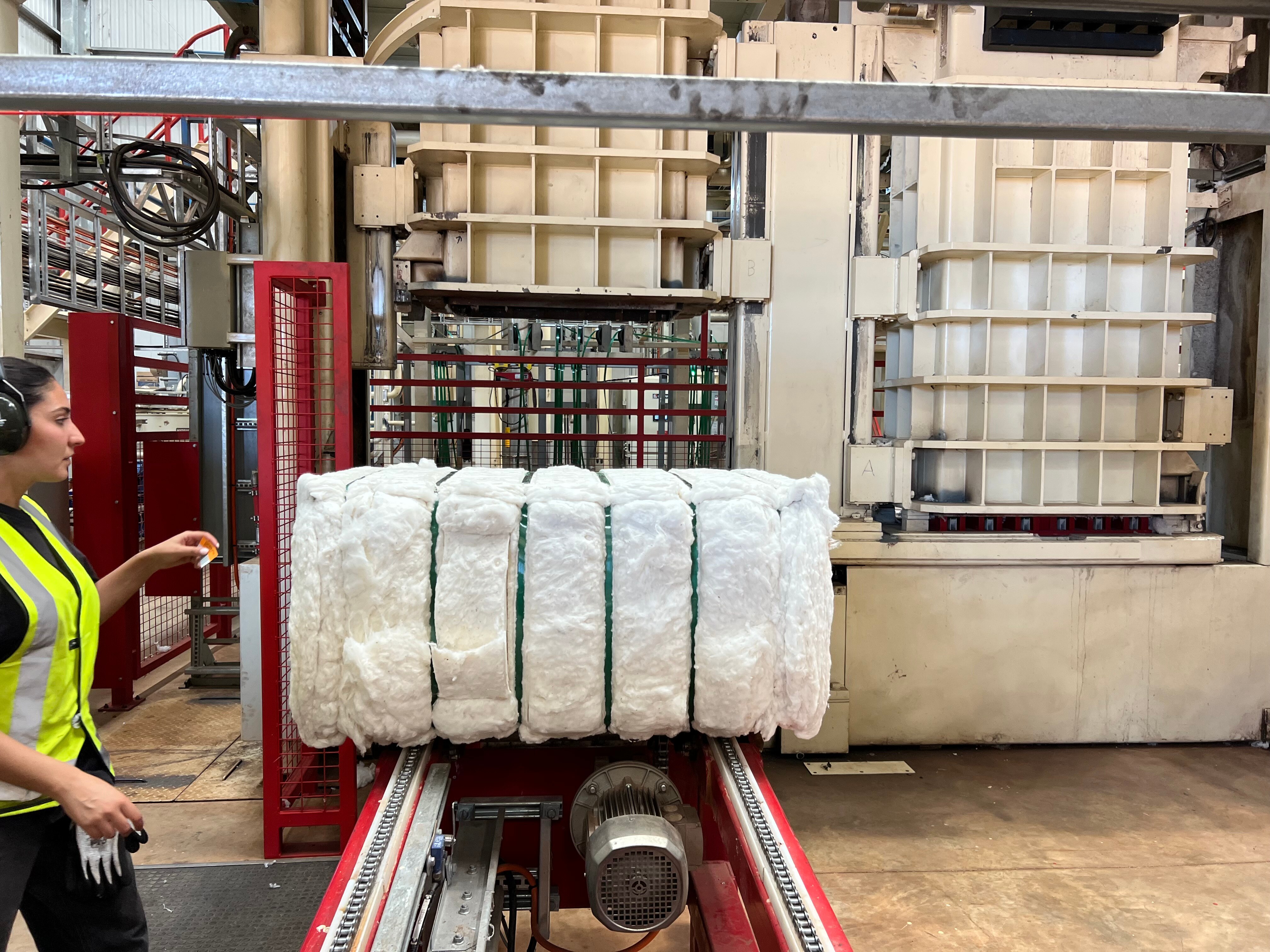 Person watching cotton bale being processed.
