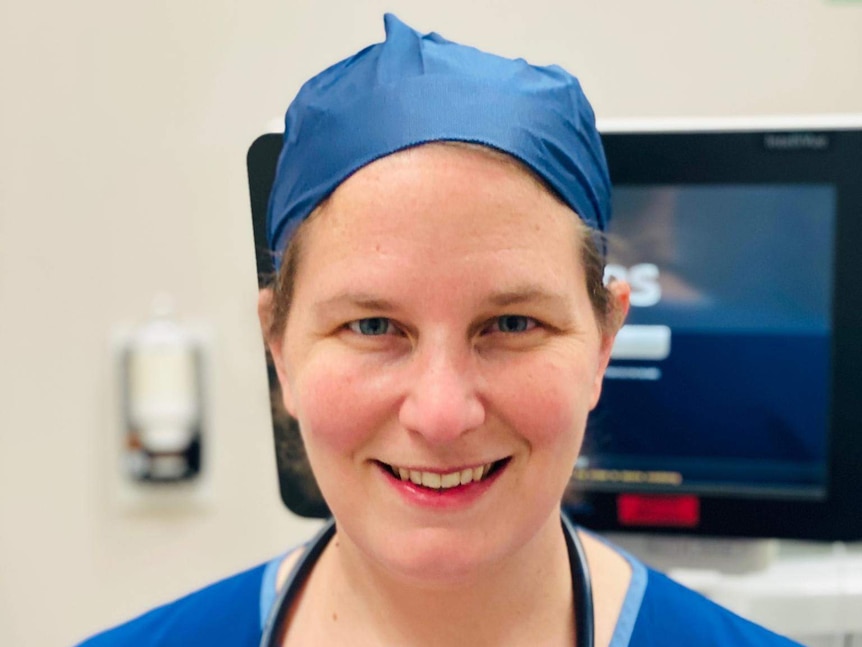 A young woman wearing scrubs and a surgical hat with a stethoscope around her neck.