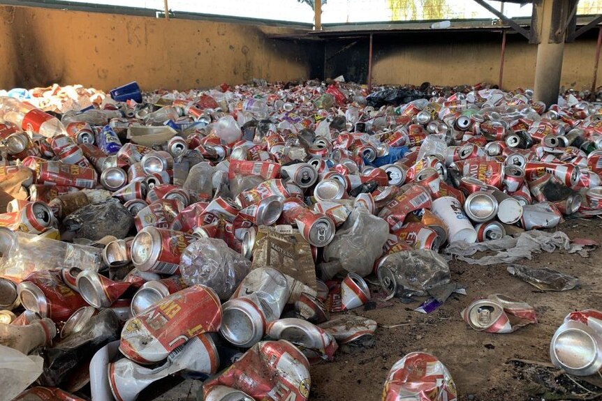Image of empty cans of alcohol littering the ground under a public area in Fitzroy Crossing in Western Australia.