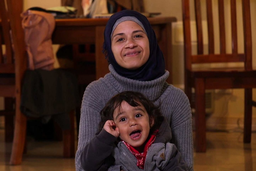 Tina sits on the floor of her Australian home with her son Mohammad