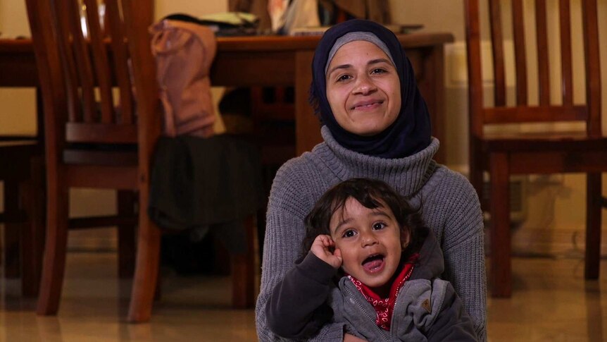 Tina sits on the floor of her Australian home with her son Mohammad