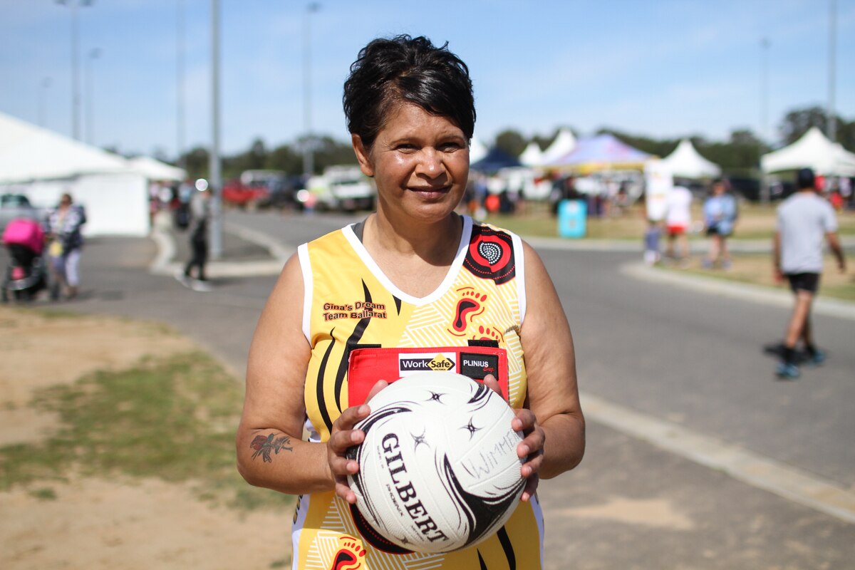 Belinda Hayden from Gina's Dream Team from Ballarat holding a netball ball and smiling.