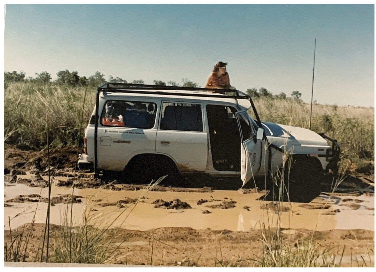 A woman leans out of a bogged car