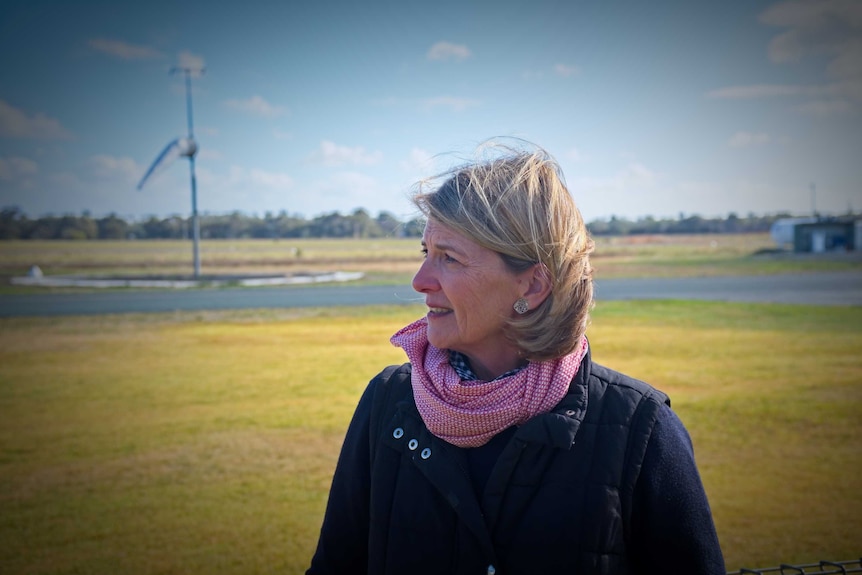 Middle-aged lady with dark blonde hair looks away from the camera while standing at the Aerodrome.