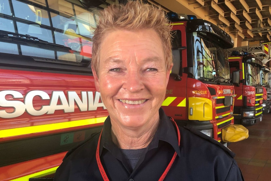 A woman in front of fire trucks in a fire station