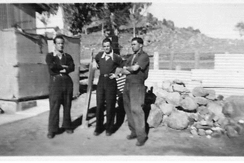 Black and white photograph of three men near a pile of rocks in the 1940s