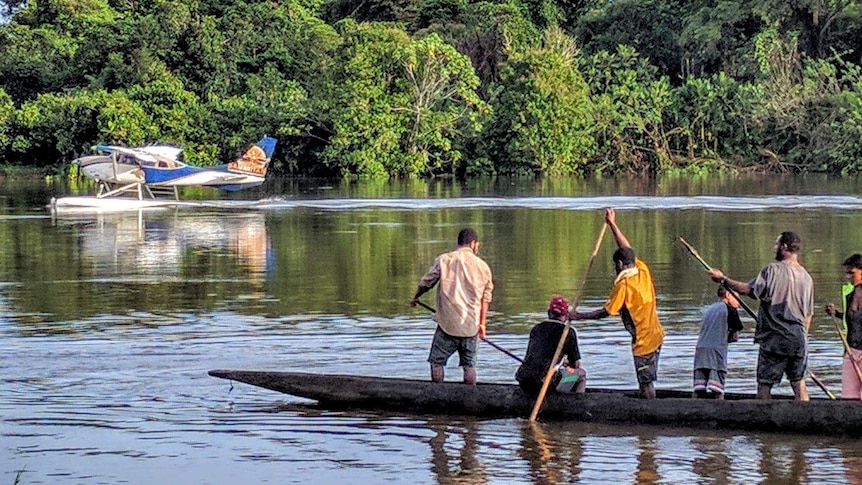 Villagers paddle a canoe by a Cessna 206 along the Sepik River. (Photo: Mark Palm)