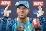 Cricketer David Warner speaks to media at a press conference, talking and holding his hands up