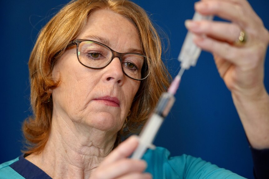 A close up of Fiona Marsden carefully drawing a vaccine into a syringe.