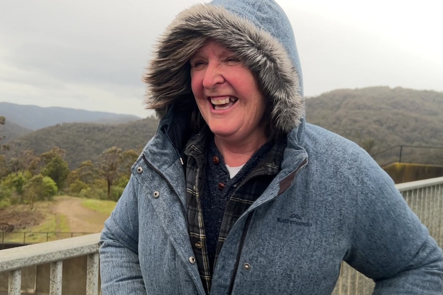 A woman in a blue jacket smiles at someone off camera.