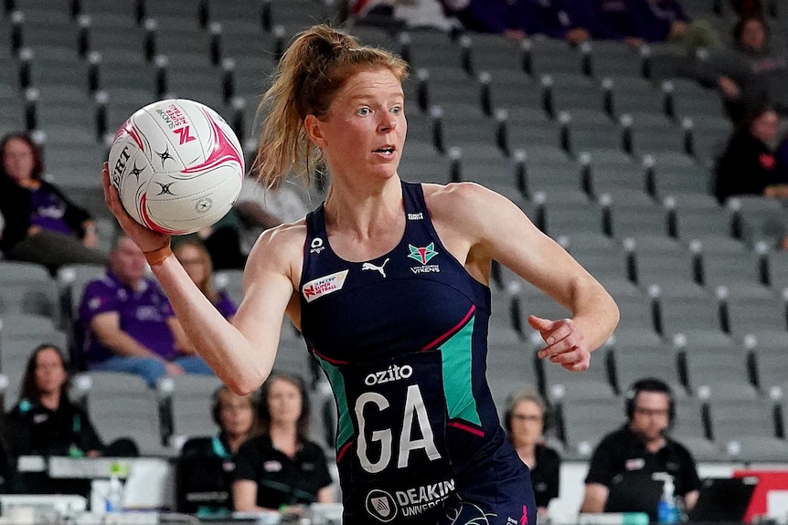 A Melbourne Vixens Super Netball player looks to the pass the ball with her right hand against the West Coast Fever.