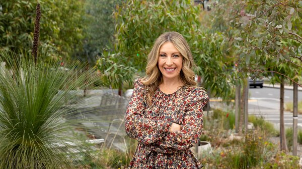 Richelle Hunt stands in a garden surrounded by green plants.