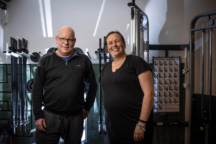 A man and a woman standing next to gym equipment. 