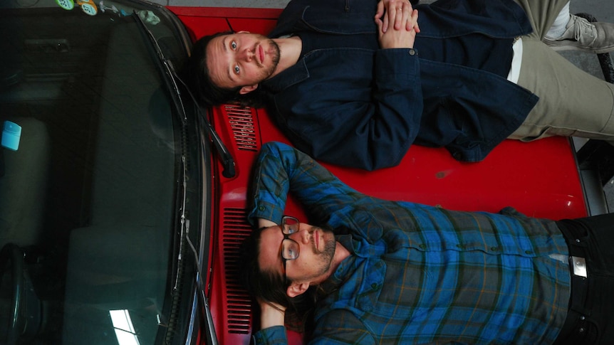 daydreams duo lying ontop of a red old school car