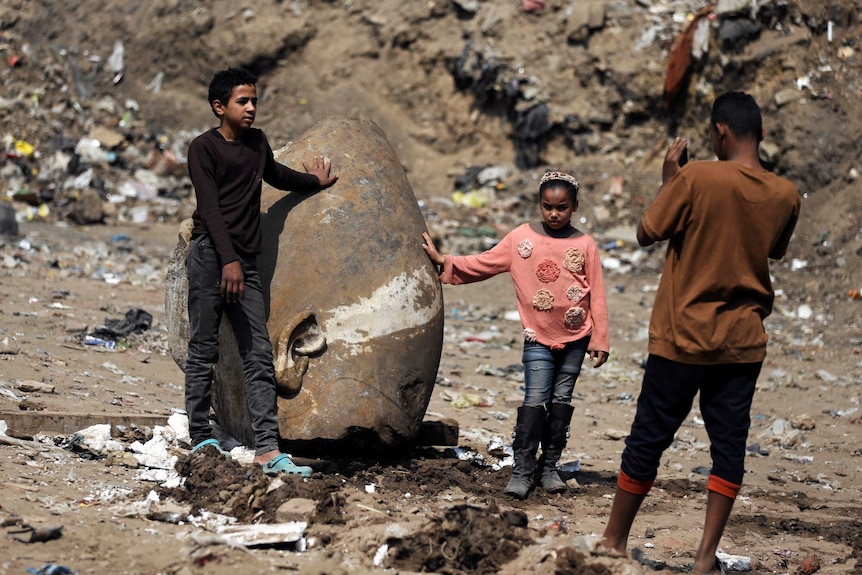 Residents rest against what appears to be the head of an unearthed statue