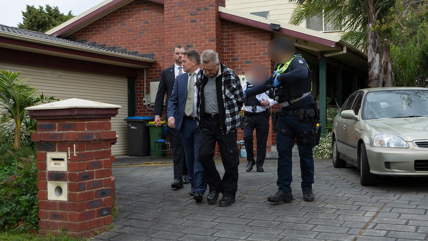 A man is led away from a home by police.