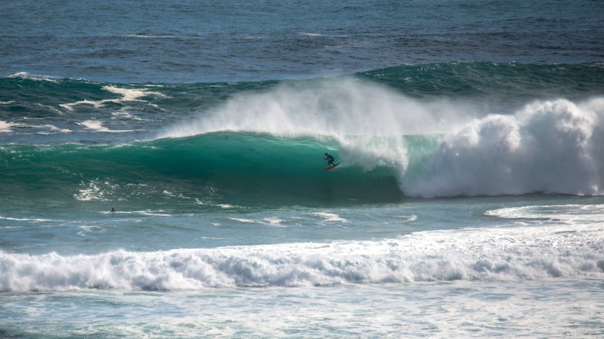 A surfer rides a large wave.