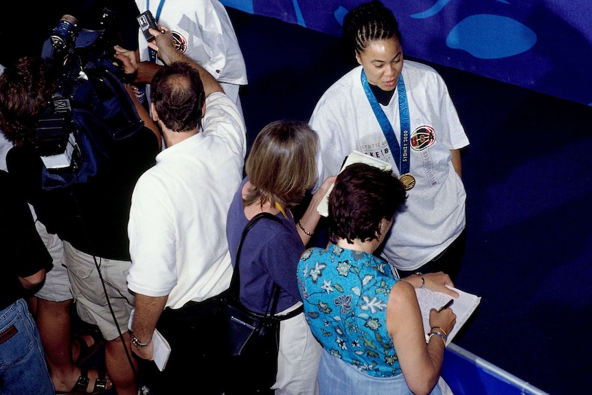 Two female reporters interview a female swimmer.