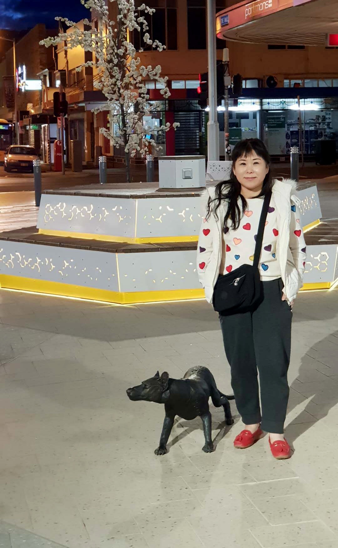 夜晚，一名女子站在城市里的购物中心里。