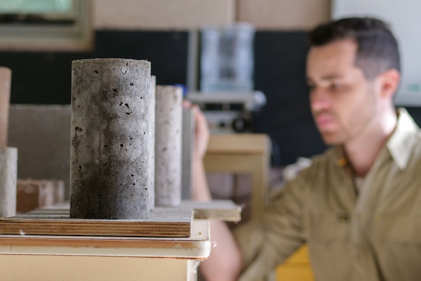 Several small grey concrete blocks lined up in a row with a man blurred in the background