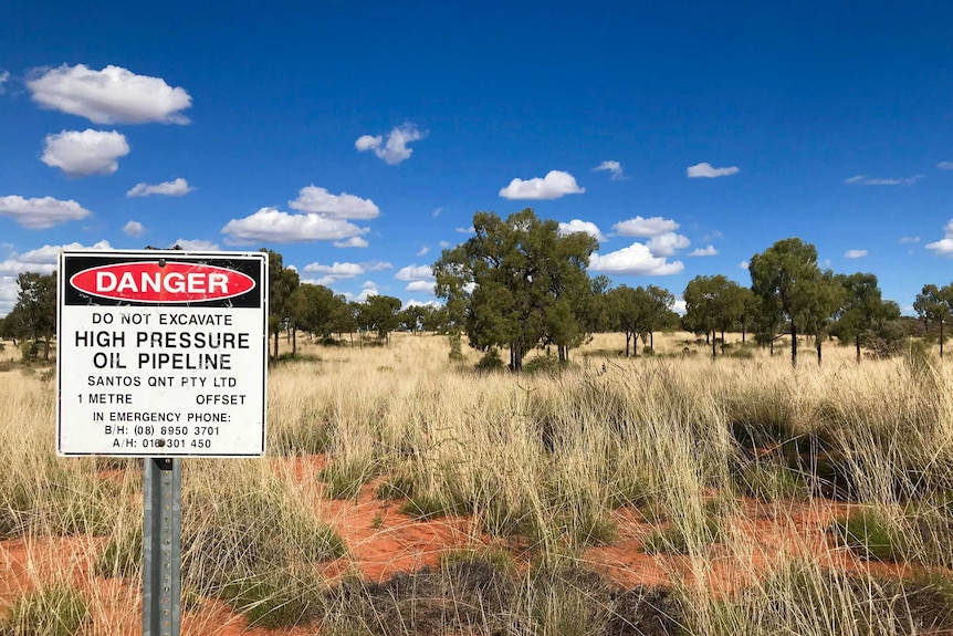 Sign with santos on it in front of red dirt with spinifex.