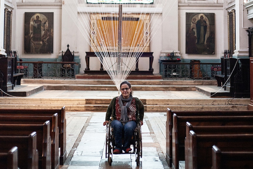 Colour photograph of artist Noëmi Lakmaier inside the foyer of a church.