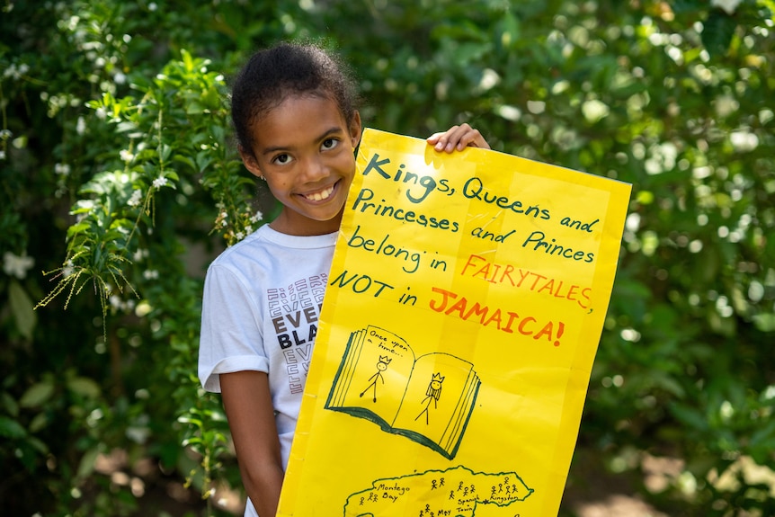 Una niña con un cartel que dice: "Reyes, reinas y princesas y príncipes pertenecen a los cuentos de hadas"