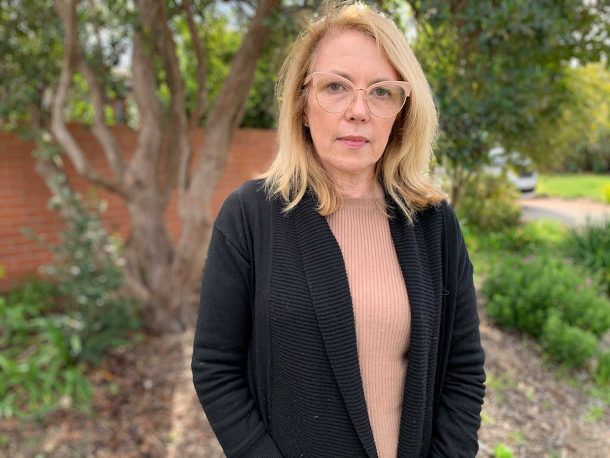 A woman with glasses looks serious.