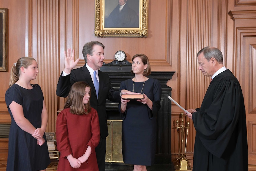 Brett Kavanaugh raises his right hand as he takes the oath