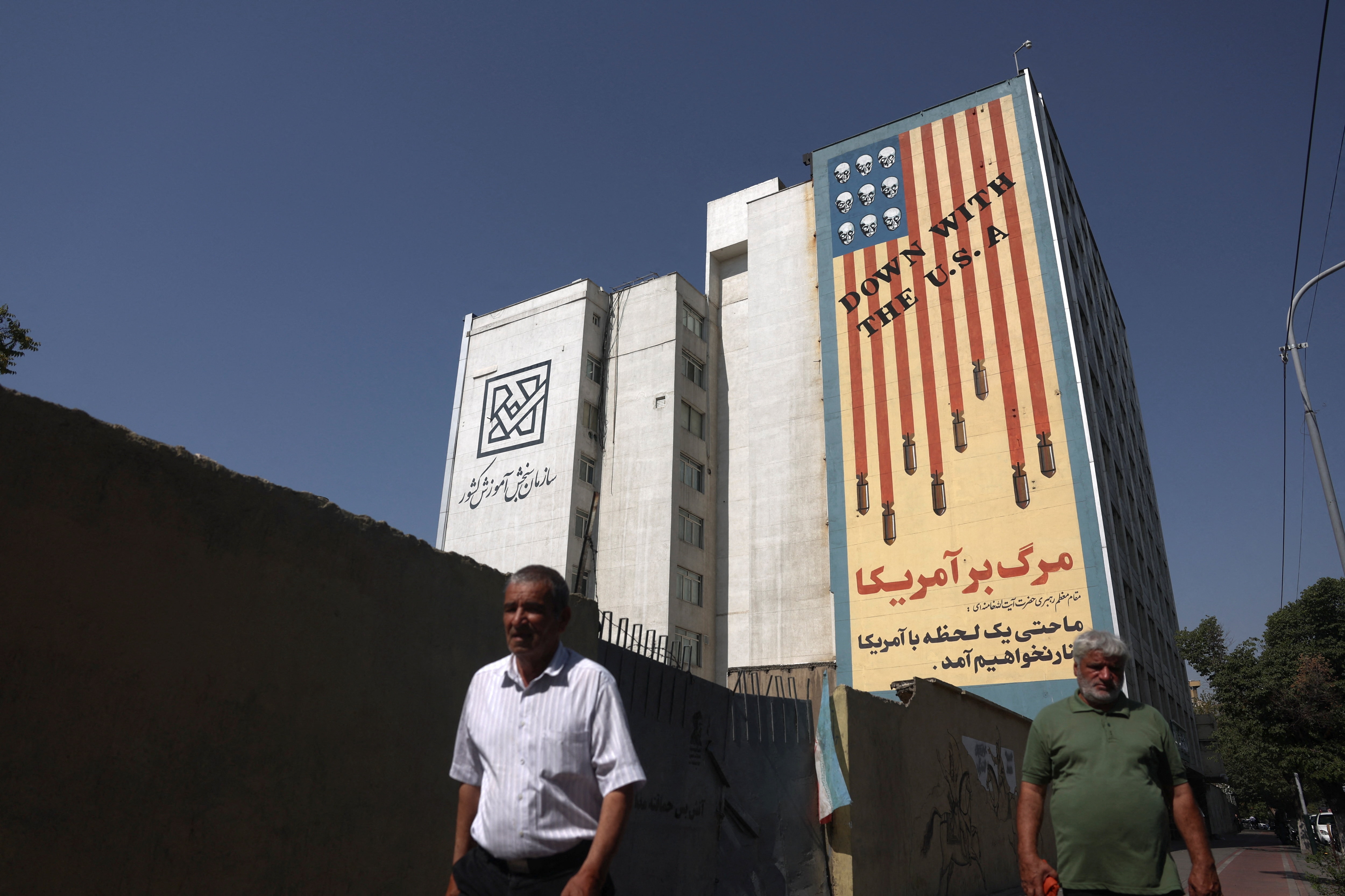 A man walks next to a mural with a bloodied US flag.
