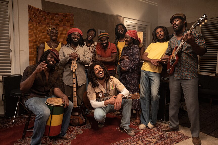 A group of people, mostly men holding instruments, smiling and laughing
