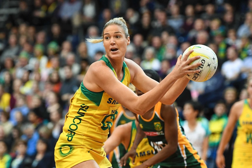 Caitlin Bassett holding the ball in two hands looking to pass for the Diamonds.