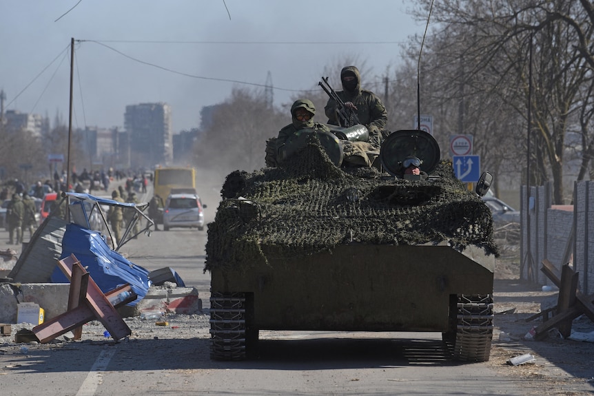 Servicemen drive an armoured vehicle.