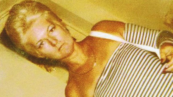 An angled shot of murdered Perth brothel madam Shirley Finn standing wearing a black and white striped top.