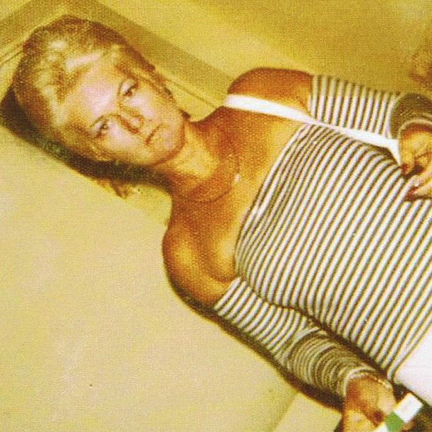 An angled shot of murdered Perth brothel madam Shirley Finn standing wearing a black and white striped top.