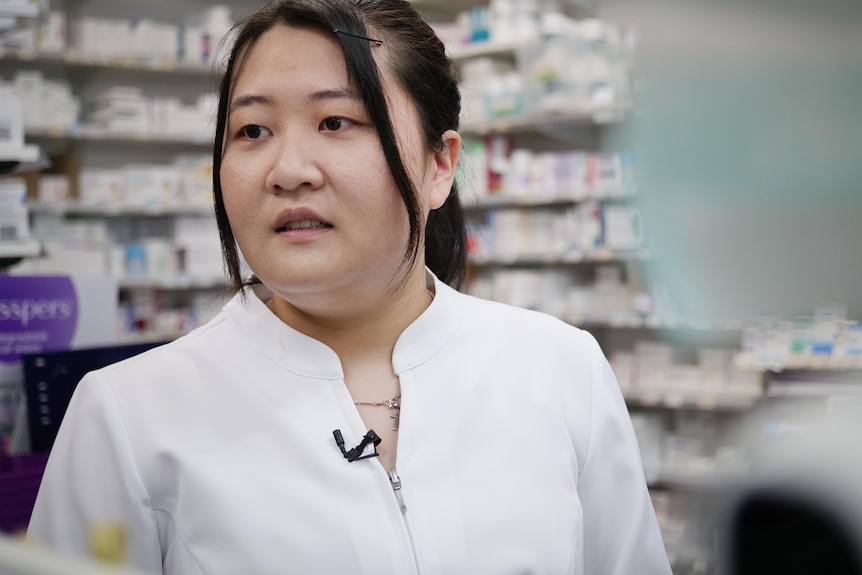 Judy Lam wearing a crisp white pharmacists uniform, looking to the side.