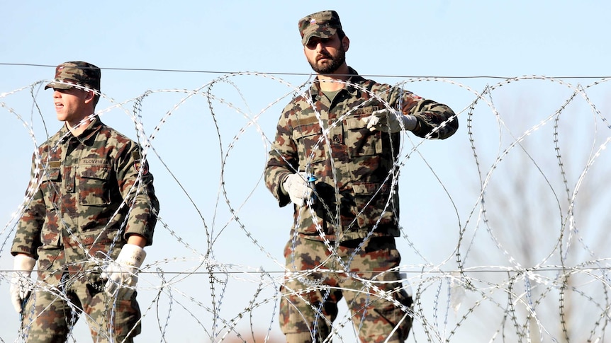 Slovenian soldiers set up barbed wire fences