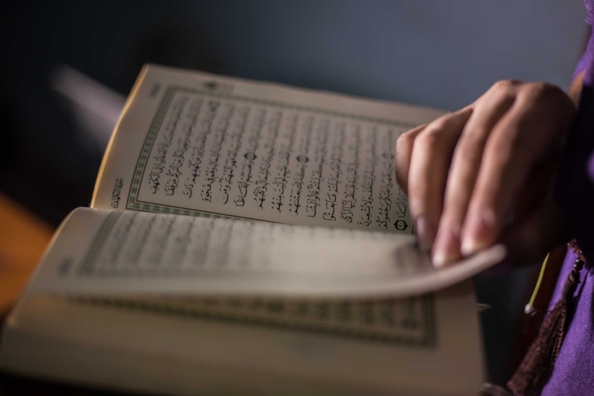 A close up of the Qu'ran being read, showing the text and pages.